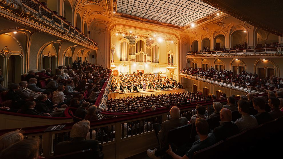 Konzertsaal mit Orchester auf der Bühne, und Publikum