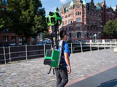  Mann mit 360 Grad-Kamera auf dem Rücken auf einer Brücke