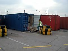  Ein Mann mit Atemschutzmaske öffnet einen Importcontainer