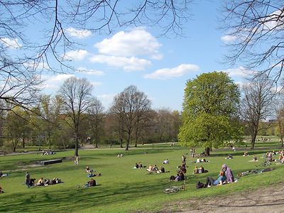  Personen sitzen im Schanzenpark in Hamburg, wenige Wolken