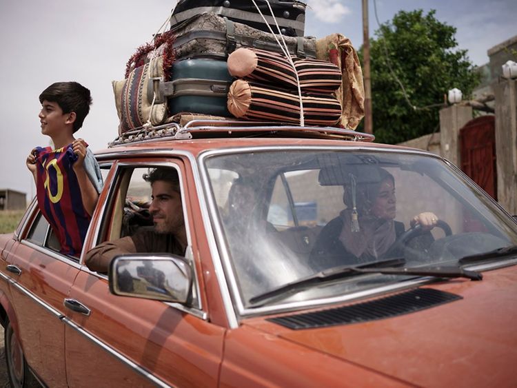  Eine dreiköpfige Familie sitzt gemeinsam im Auto. Der Sohn hält ein Messi-Trikot aus dem Fenster.