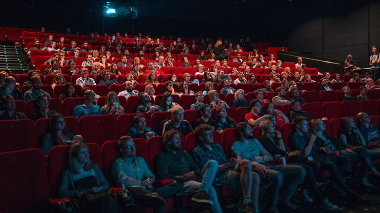  Publikum auf roten Samtsitzen im Kinosaal