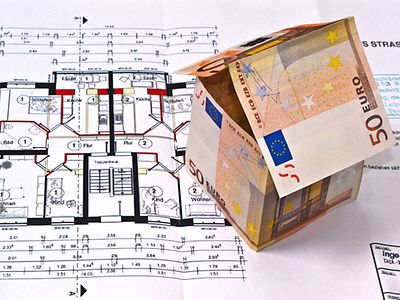  Kleines Hausmodell aus gefalteten Geldscheinen auf Plan mit Grundriss