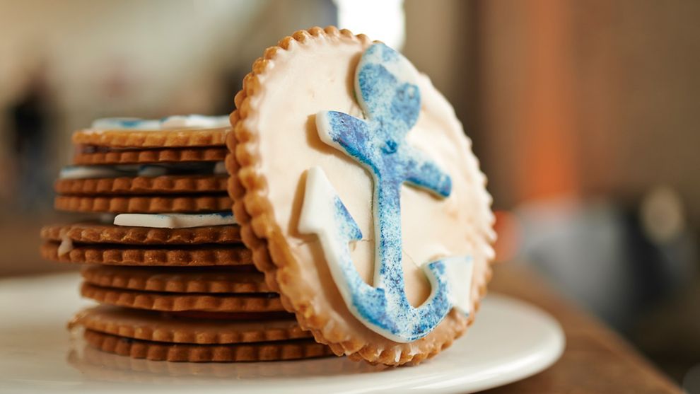 Ein Keks mit einem blauen Anker aus Zuckerguss dekoriert