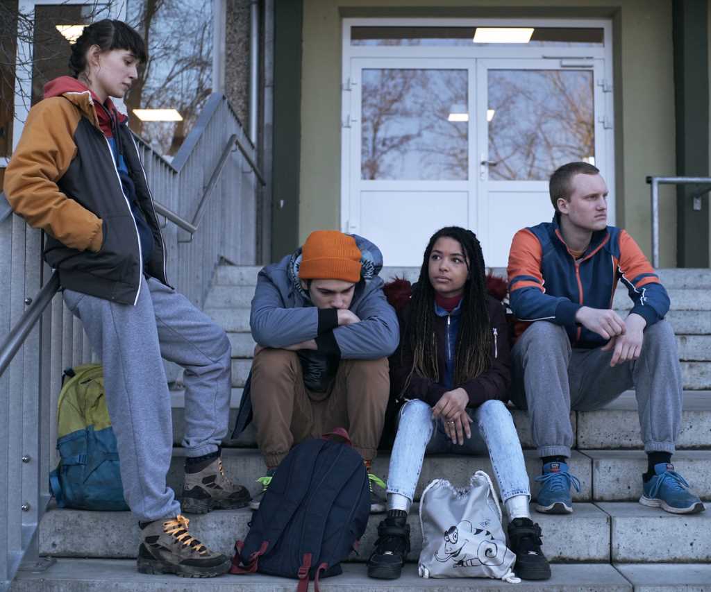 Vier junge Menschen sitzen nebeneinander auf einer Treppe.