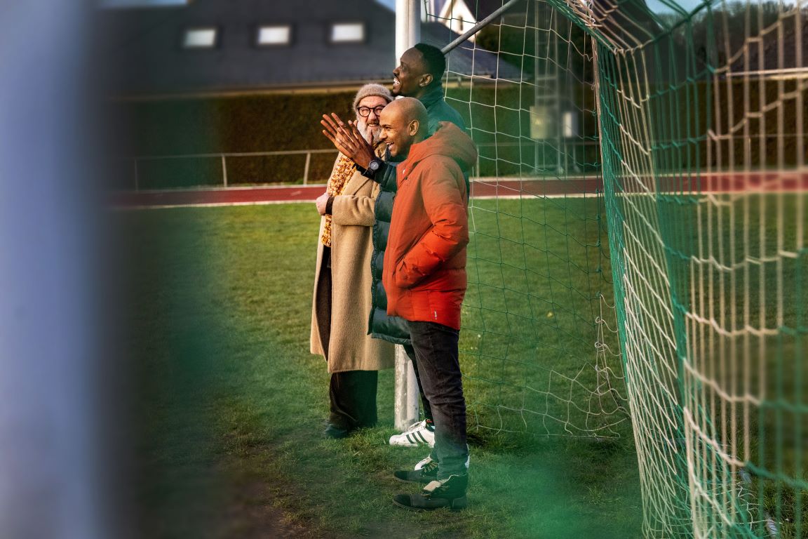 Drei Männer stehen in einem Fußballtor.