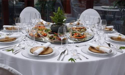 Weiß gedeckter Tisch mit Tellern und Essenplatte in der Mitte