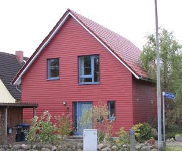 Außenansicht eines komplett roten Hauses mit blauen Fensterrahmen