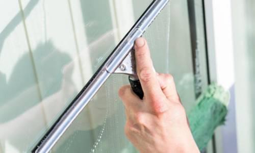 Hand reinigt Fenster mit einem Fensterabzieher