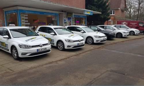 6 geparkte weiße Autos vor der Fahrschule