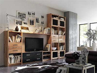 Eine Anbauwand mit offenen Fächern, Ablagen und Schubladen aus Kieferholz steht an einer Wand in einem Wohnzimmer