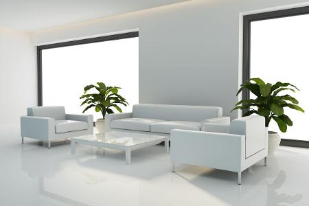 Ein weiß gestrichenes Wohnzimmer mit zwei großen, bodentiefen Fenstern, einer weißen Sitzgruppe, bestehend aus einem Sofa und zwei Sesseln, einem Tisch und einem weißem Teppich, auf weißen Fliesen