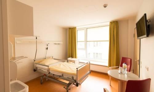 Patientenzimmer mit Krankenbett, Tisch und Fernseher