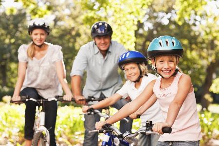Frau, Mann und zwei Kinder fahren auf einem Fahrrad- alle haben einen Helm auf