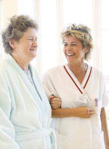 Krankenschwester mit Patientin, eingehakt lachen