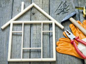 Hammer, Nägel, Zange, Handschuhe und ein Haus aus Holzstückchen