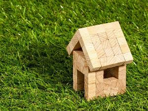 Kleines Haus aus Holzklötzen gebaut, auf einer grünen Wiese