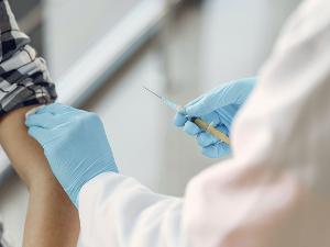 Ein Arzt mit weißem Kittel und blauen Handschuhen gibt einem Patienten eine Spritze
