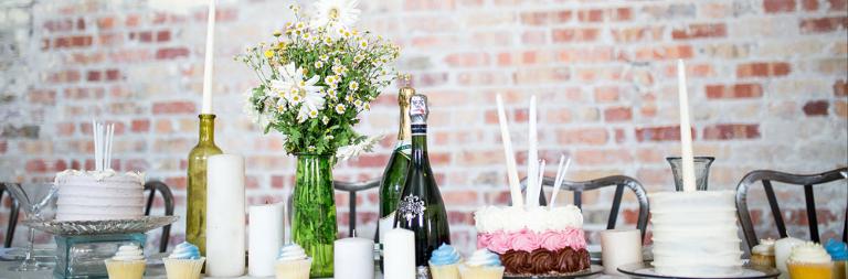 Tisch mit Blumen, Kuchen und Cupcakes darauf
