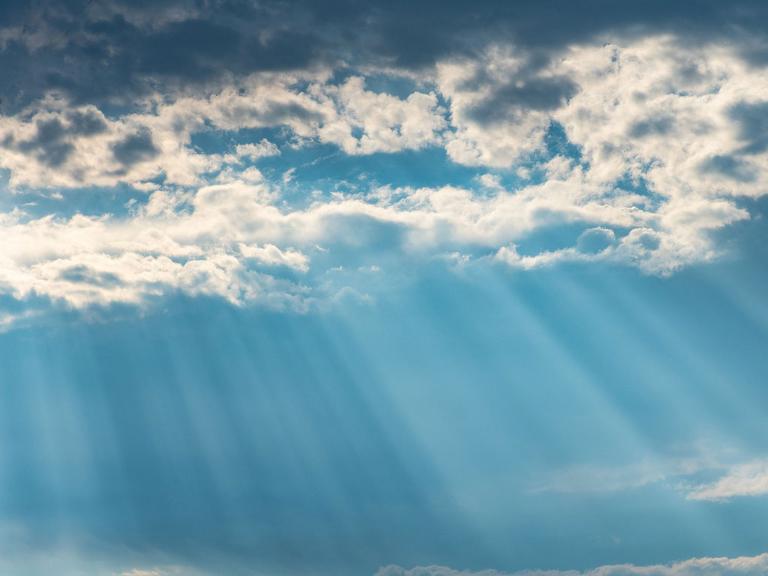 Sonnenstrahlen kommen durch die Wolkendecke am Himmel