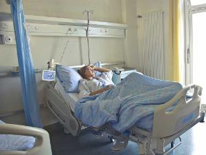 Eine weibliche Person liegt in einem Krankbett und schaut aus dem Fenster