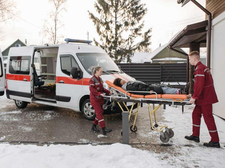 Zwei Sanitäter schieben eine Frau auf der Trage zum Krankenwagen