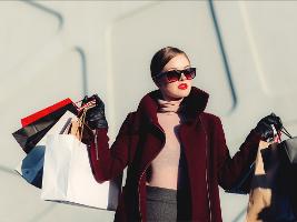 Frau mit Sonnenbrille hält mehrere Einkaufstüten in beiden Händen