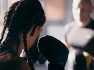 Frau mit geflochtenen Zöpfen und Boxhandschuhen an macht Boxübungen