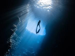 Frau taucht aus den Tiefen des Meeres nach oben, Aufnahme von unten