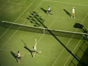 Tennisplatz von oben fotografiert, vier Personen spielen ein Doppel