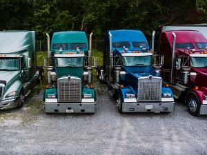 Vier Amerikanische Trucks stehen auf einem Schotterparkplatz nebeneinander- Frontansicht