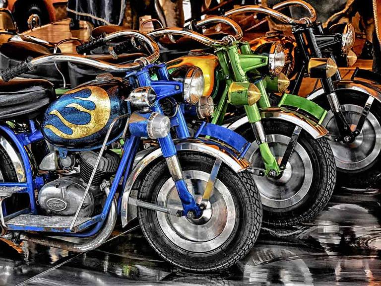 Farbig lackierte Motorräder stehen nebeneinander, seitliche Aufnahme