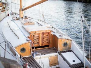Ein weißes Segelboot mit Holzverkleidungen an der Tür und den Fenstern zum Unterdeck