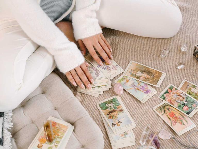 Eine Frau hat Tarotkarten und Steine vor sich liegen