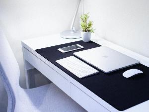 Apple IPhone, Laptop und dazu passende Tastatur und Maus auf dem Schreibtisch liegend