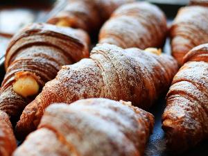 Man sieht mehrere Croissants mit Puderzucker bestäubt in der Auslage eines Bäckers