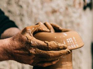 Hände formen eine Vase aus Lehm
