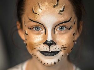 Das Gesicht eines Mädchens in der Nahaufnahme, angemalt als Tiger