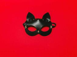 Eine schwarze Katzenmaske auf rotem Hintergrund