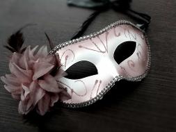 Eine weiße Maske mit einer Blume an der Seite und Straßsteinen umrahmt, mit einem schwarzen Band zum festmachen