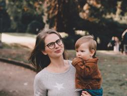 Eine Frau mit Brille hat ein Kind auf dem Arm