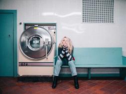 Eine Frau sitzt auf einer Bank neben einer Waschmaschine