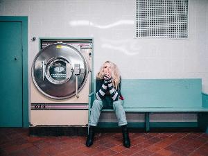 Eine Frau sitzt auf einer Bank neben einer Waschmaschine