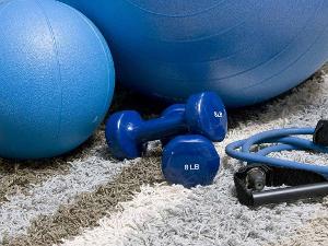 Blauer Gymnastikball, Hanteln und eine Seil auf einem Teppich liegend