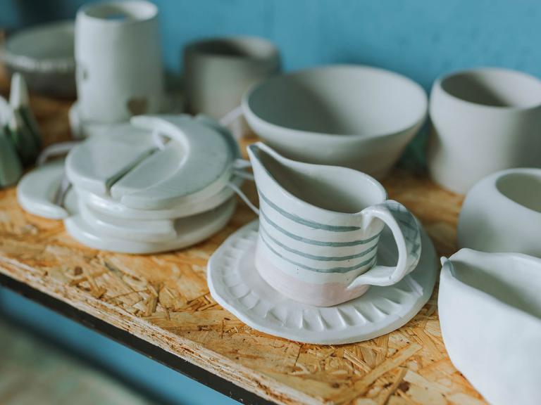 Keramikprodukte stehen in einem Regal- Milchkanne, Schüssel, Becher und ein Stövchen