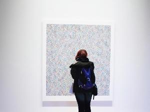 Eine Frau steht vor einem Bild das an einer weißen Wand hängt