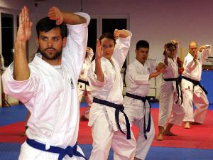 Menschen in Karateanzügen machen gemeinsam Sportübungen