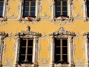 Gelbes historisches Gebäude mit Stuckelementen um die Fenster herum