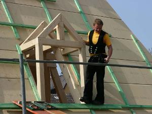 Ein Mensch steht vor einer Holzkonstruktion für ein Dachfenster