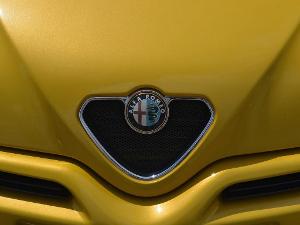 Gelber Motorhaube eines Alfa Romeo, man sieht das Emblem in der Nahaufnahme